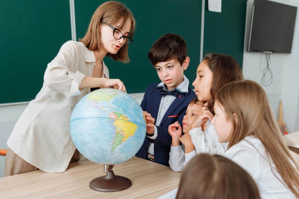 A teacher with her students examining a globe in the classroom