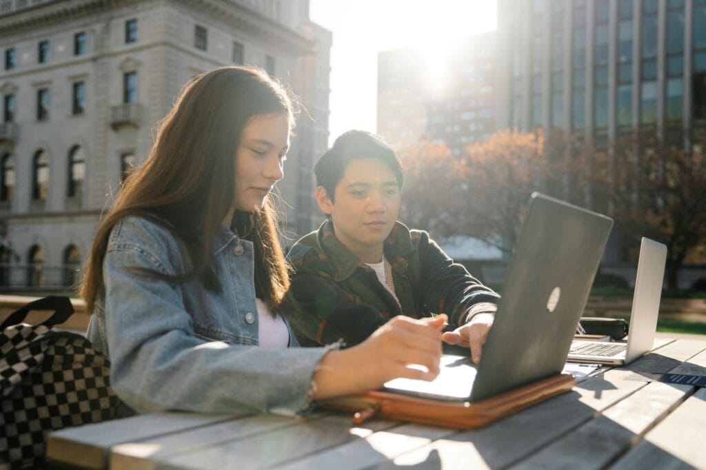 High school students studying together with the school building in the background