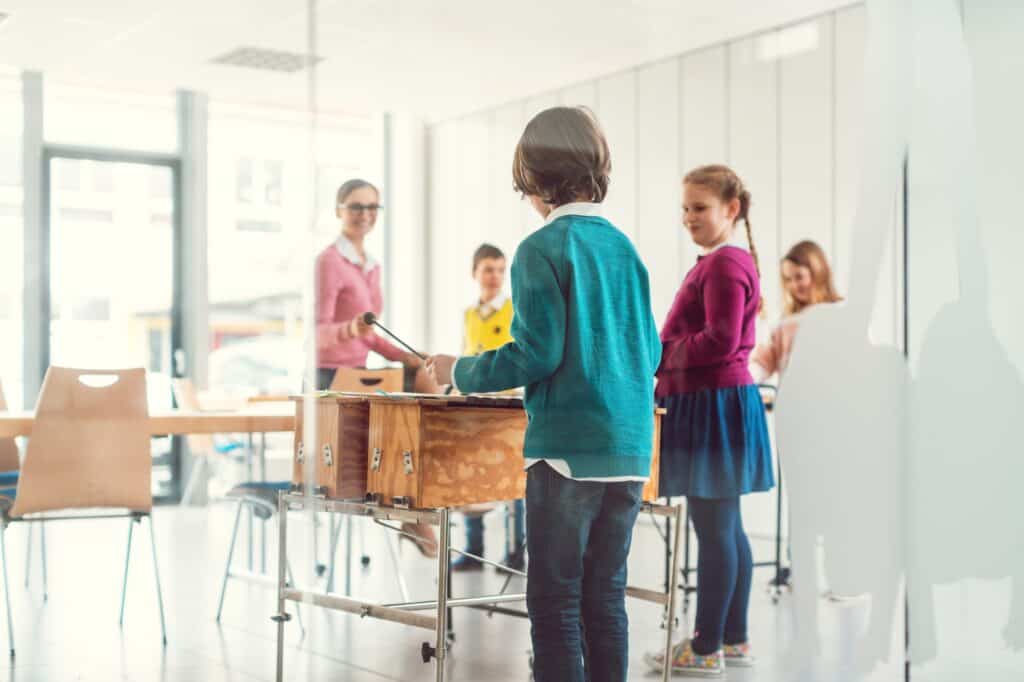 The teacher and students in music class use xylophone