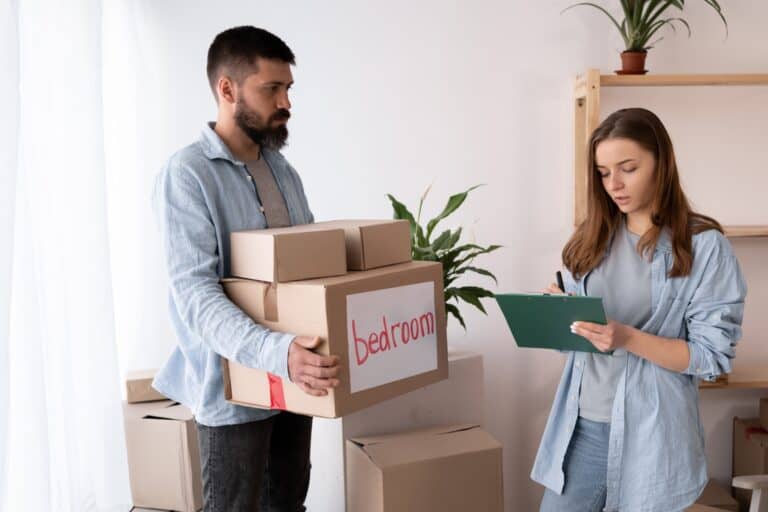 Professional movers with matching long-sleeves polo holding boxes and clipboard in the concept of 'Ealing removals cost'.